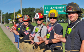 Firefighters wave American flags along the highway
