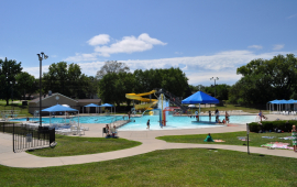 photo of pool with zero depth entry surrounded by green grass and sidewalks