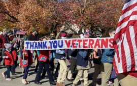 veterans day parade photo with people carrying veterans banner