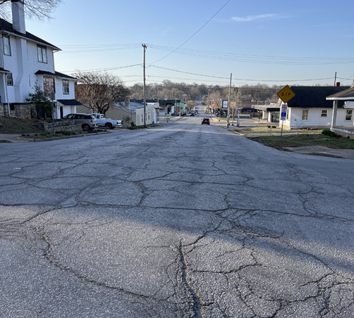 Photo shows road with cracks and uneven driving surface along Seventh Street near Seneca Street