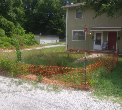 Photo of house with a sink hole blocked off with orange fencing