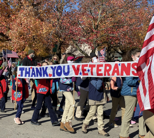 Children carry banner in Veterans Day parade that reads, "Thank You Veterans"