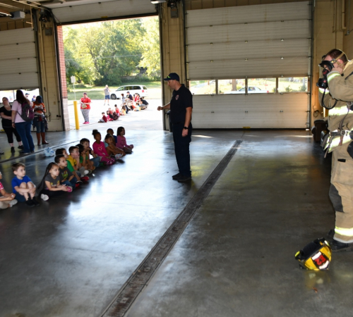Fire fighter in gear in front of children