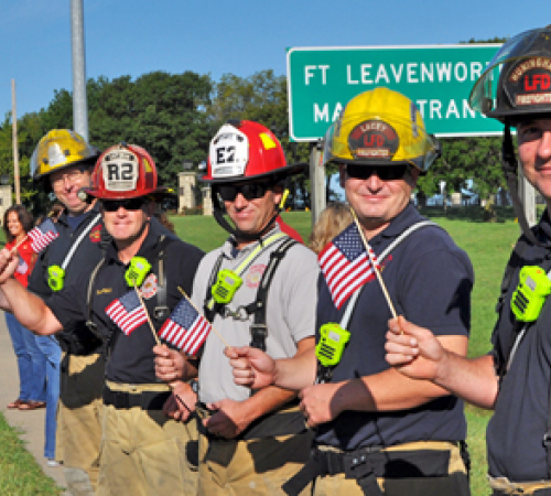 Firefighters wave American flags along the highway