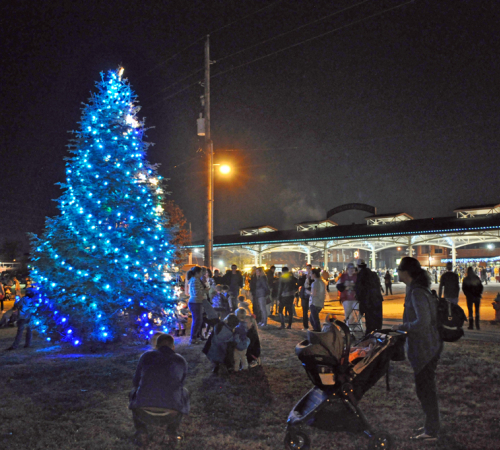 family by the lighted mayor's tree outside at Haymarket Square