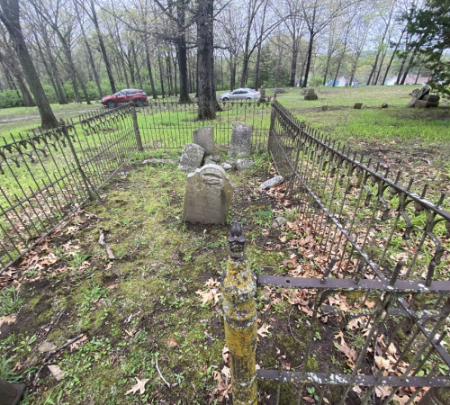 set of grave stones in a field surrounded by a fence