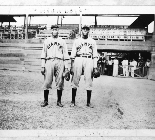 Two black men in Giants baseball uniforms on a baseball field