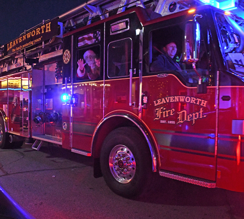santa and child wave from inside a fire truck