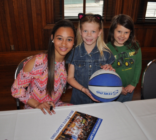 Girls smiling with signed basketball