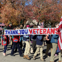 Children carry banner in Veterans Day parade that reads, "Thank You Veterans"