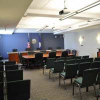 Photo of Commission room with chairs for the public, a podium for the public in front of a desk for elected officials