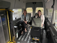 Two women seated comfortably in bucket seats with enough space behind a wheelchair lift for a RideLV van