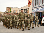 Members of the U.S. military in uniform march on downtown street during parade