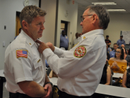 Fire Chief Gary Birch, right, pins promotional indicia upon newly promoted fire staff