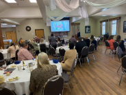 Business people sitting at tables and watching a presentation on a screen