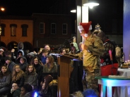 soldier in uniform addresses crowd wearing red hat trimmed with white
