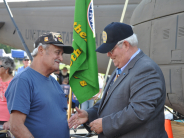 Charles Hagemeister shakes the hand of a veteran with a "Vietnam Veteran" hat wearing his Medal of Honor.