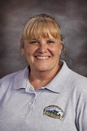 Woman with brown hair in ponytail with bangs in white polo shirt with city logo