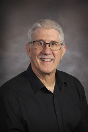 Man with gray hair, glasses and black button-down shirt