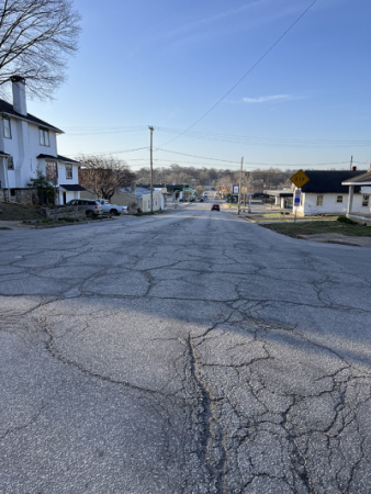 Photo shows road with cracks and uneven driving surface along Seventh Street near Seneca Street