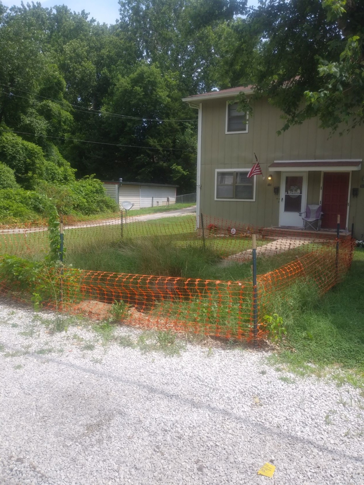 Photo of house with a sink hole blocked off with orange fencing