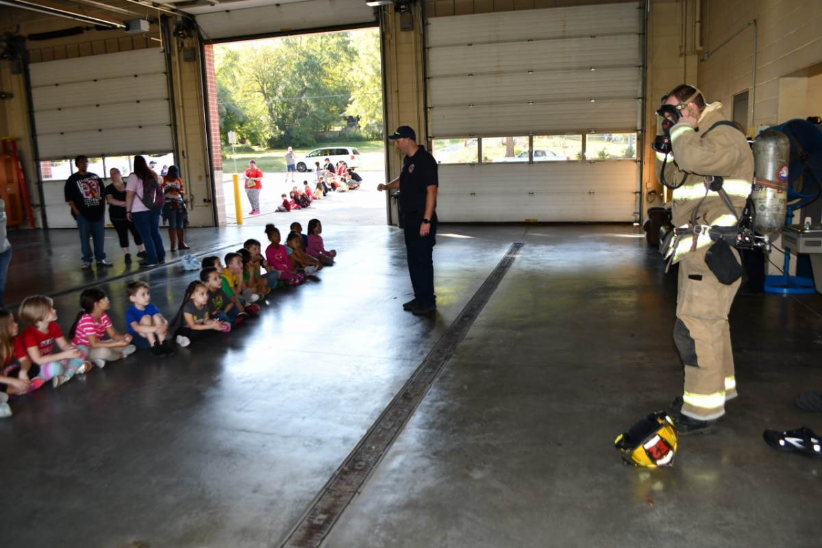 Fire fighter in gear in front of children