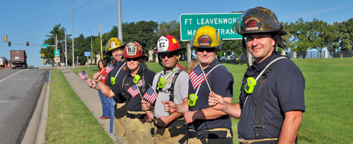 Firefighters wave American flags along the highway