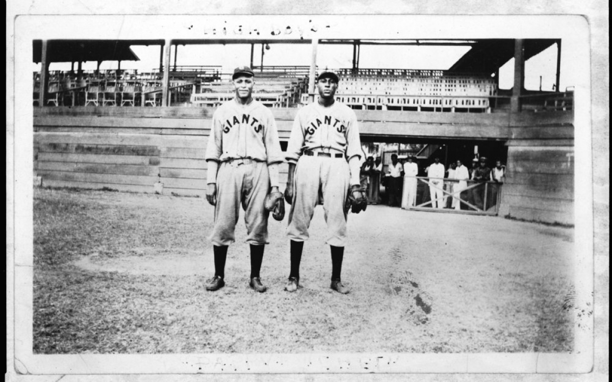 Two black men in Giants baseball uniforms on a baseball field