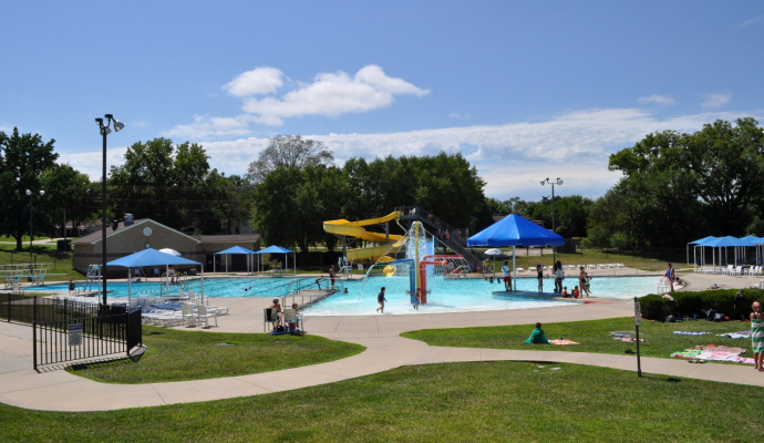 photo of pool with zero depth entry surrounded by green grass and sidewalks