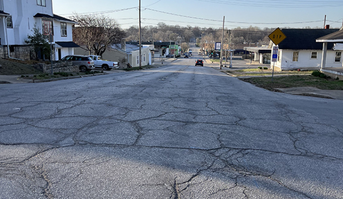Photo shows road with cracks and uneven driving surface along Seventh Street near Seneca Street
